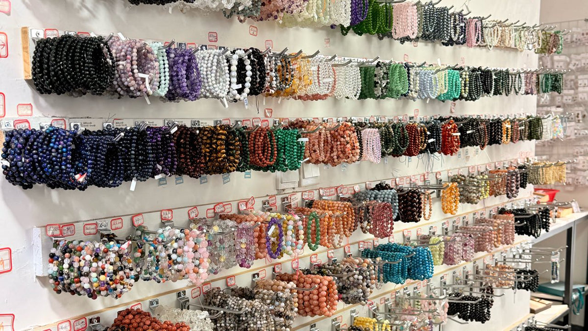Rows of beaded bracelets arranged on wall-mounted display hooks for gift-store selection.